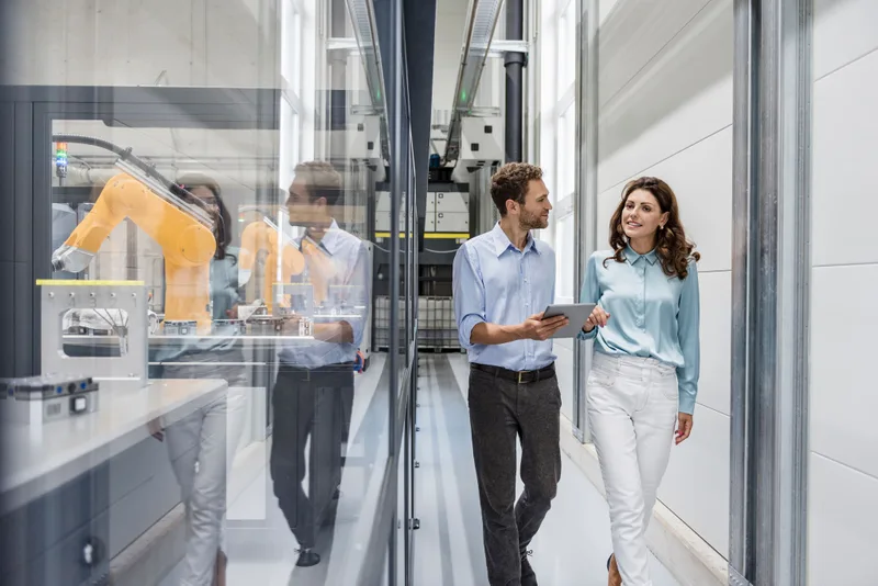 Businessman and woman having a meeting in high tech company using Stäubli robots.